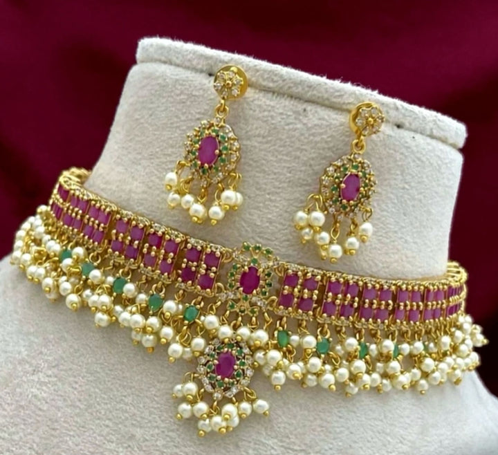 Gold necklace with pearls and red stones on a mannequin bust against a dark background