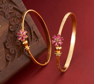 Gold bangles with pink floral designs on a red background