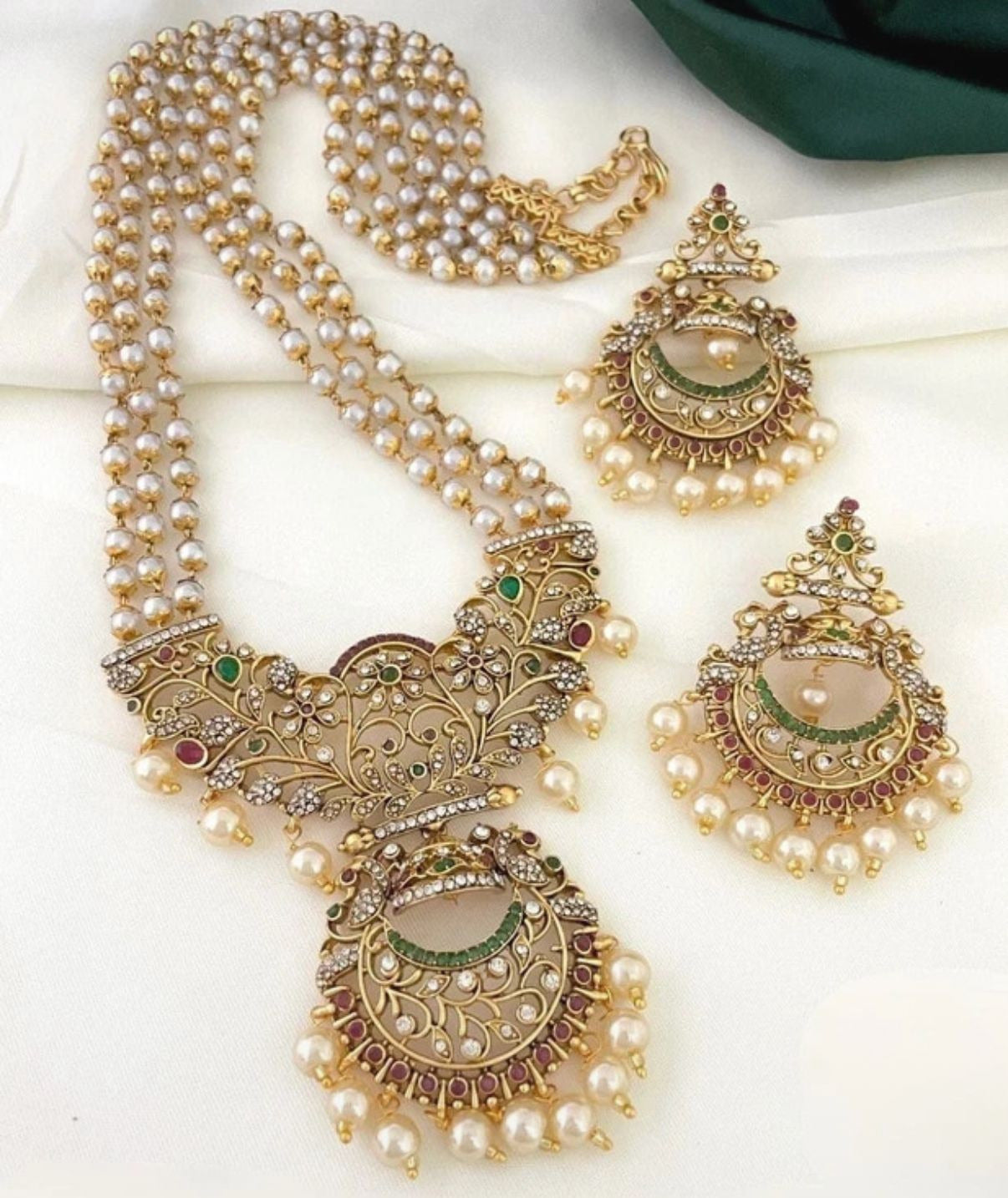 Ornate necklace with pearl strands and matching earrings on a white background