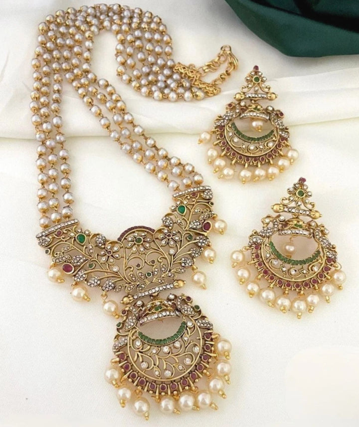 Ornate necklace with pearl strands and matching earrings on a white background