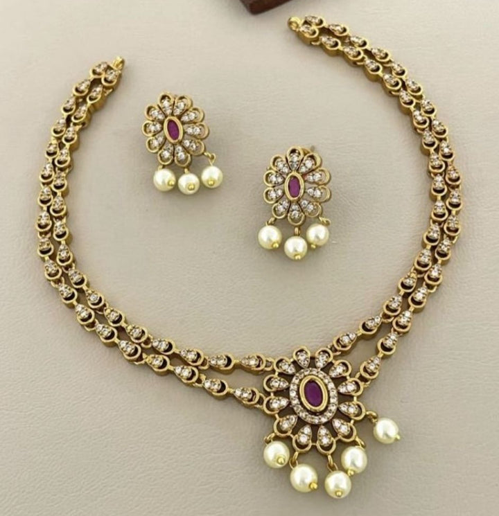 Gold necklace and earrings set on a beige background
