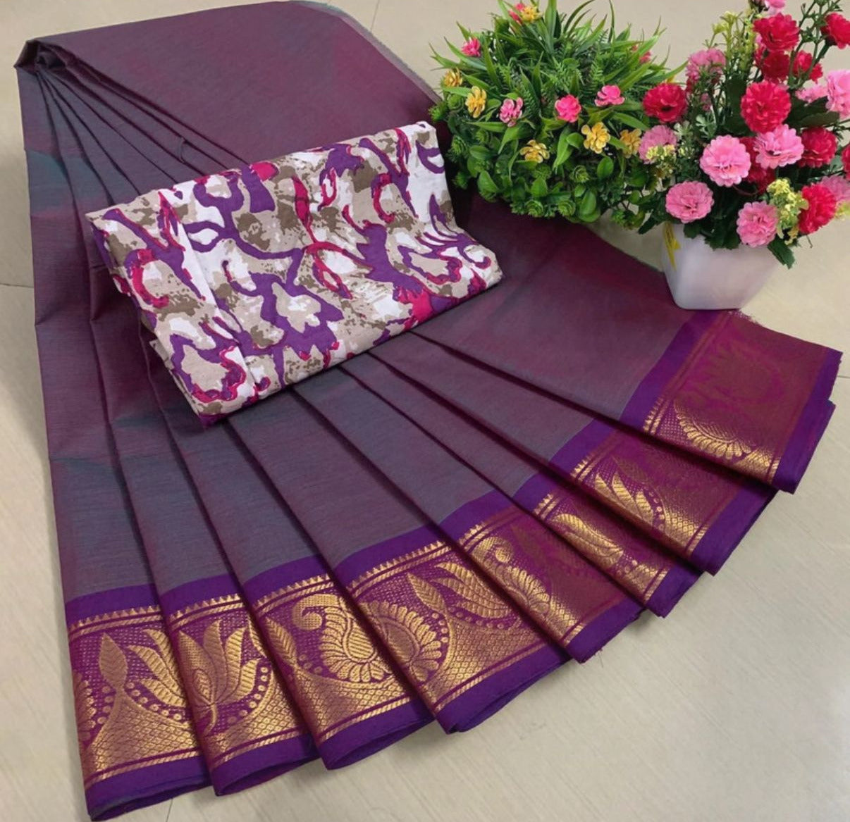 Purple saree with gold border and floral arrangement on a light background